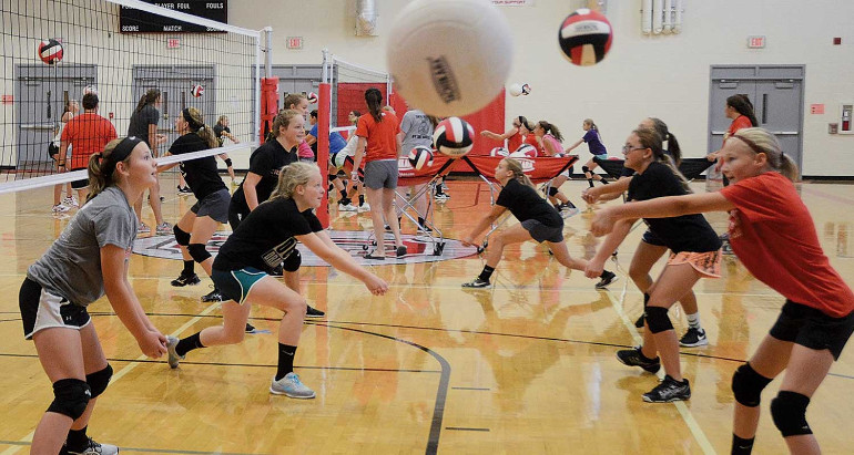 young kids playing volleyball in a gym